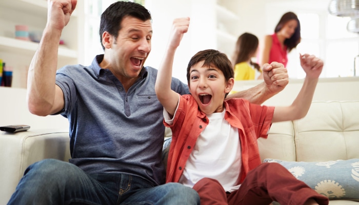 Dad Celebrating With Son On Couch Dad Celebrating With Son On Couch