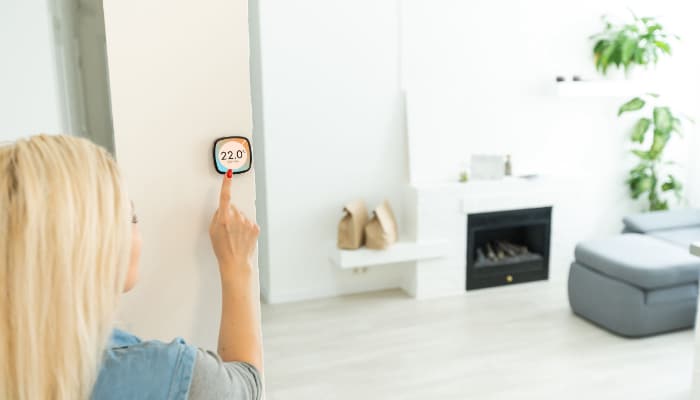 Woman Pressing Programable Thermostat In Livingroom Woman Pressing Programable Thermostat In Livingroom